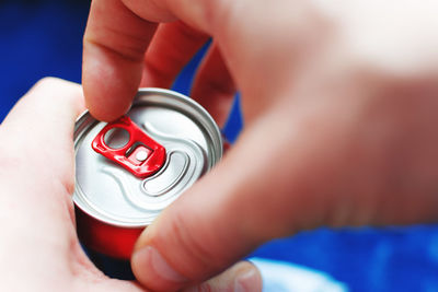Close-up of cropped hand opening drink can