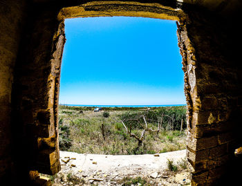 Old ruins against clear blue sky seen through window