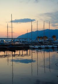 Sailboats moored on sea against sky during sunset