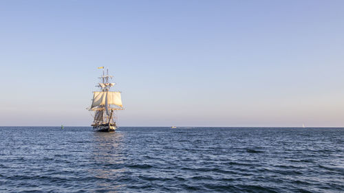 Sailboat sailing in sea against clear sky