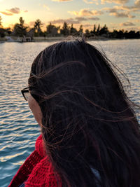 Rear view of woman in lake against sky during sunset