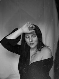 Portrait of young woman standing against wall. 