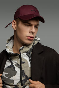 Portrait of young man wearing hat against gray background