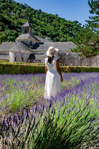 Rear view of woman standing on field against stone wall