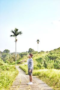 Rear view of woman walking on field against clear sky