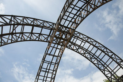 Low angle view of grid tower against cloudy sky