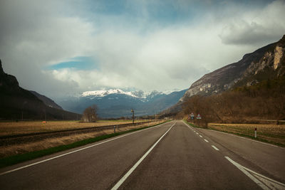 Empty road amidst mountains against sky