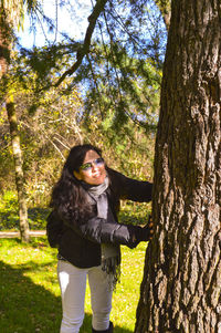Portrait of woman standing on tree trunk