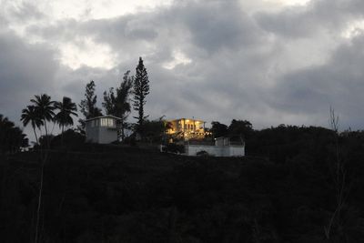 Buildings and trees on field against sky at dusk