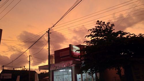 Low angle view of silhouette tree and building against sky at sunset