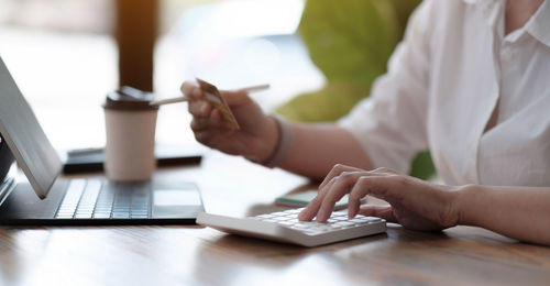 Midsection of man using mobile phone on table