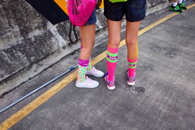 Low section of people standing on pink shoes