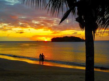 Silhouette people on beach against sky during sunset