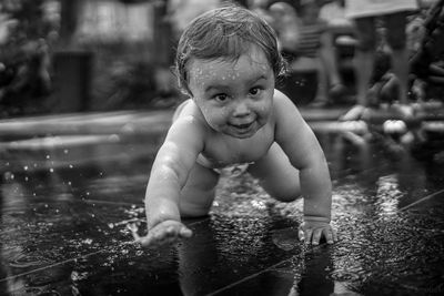Portrait of shirtless baby boy crawling at fountain