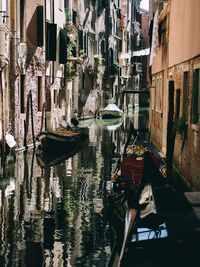 Boats moored in canal amidst buildings in city