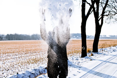 Person throwing snow while standing on road against sky