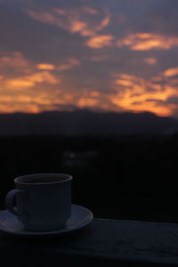 Coffee cup on table against sky during sunset