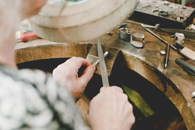 High angle view of senior female jeweler working at workbench in workshop