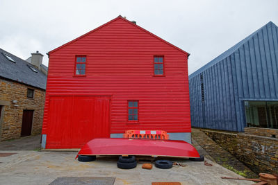 Red house by building against sky