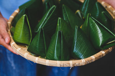 Cropped image of man holding food wrapped in banana leaves