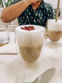 Midsection of woman holding drink on table