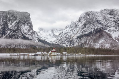 Scenic view of lake by snowcapped mountains against sky