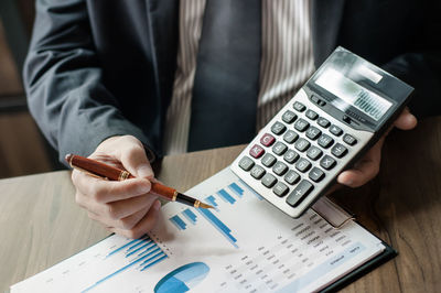 Midsection of man holding mobile phone on table