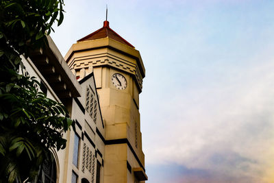 Low angle view of clock tower amidst buildings against sky