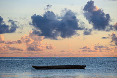 Boat in sea against sky during sunset