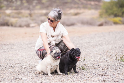 Senior woman with pugs on field