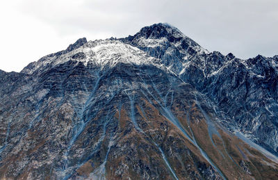 Low angle view of snow covered mountain against sky