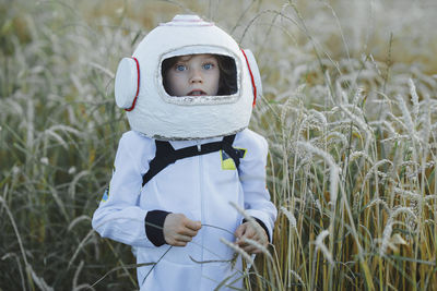 Cute boy wearing space suit and helmet at field