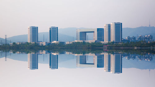 Reflection of buildings in lake against clear sky