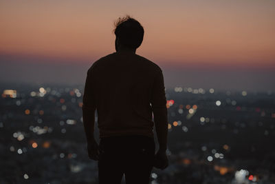 Rear view of man standing against sky during sunset