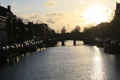 Bridge over river amidst buildings in city against sky
