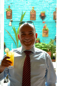 Portrait of smiling businessman holding drink at restaurant