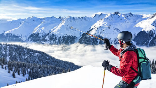 Man skiing on snow covered mountain against sky