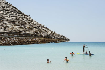 People on sea shore against clear sky