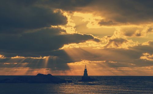 Scenic view of sea against dramatic sky during sunset