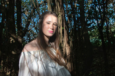 Portrait of young woman looking away in forest