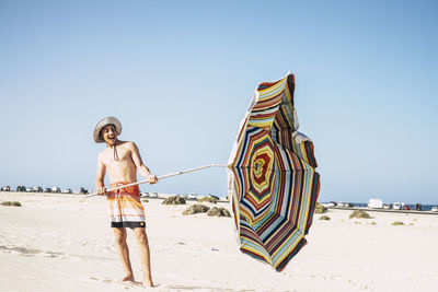 Traditional windmill on beach against clear sky