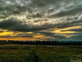 Scenic view of dramatic sky over land during sunset