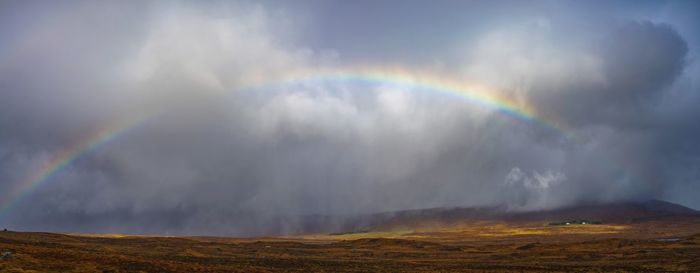 Scenic view of rainbow over landscape against sky