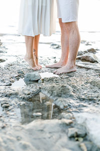 Low section of couple standing on beach