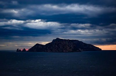 Scenic view of sea and mountains against dramatic sky