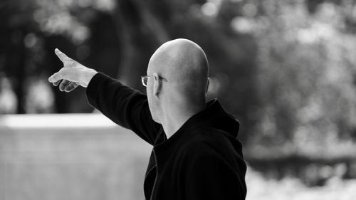 Side view of man gesturing against blurred background