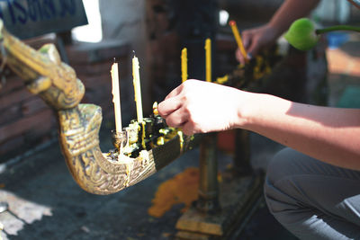 Midsection of person holding burning candles in temple