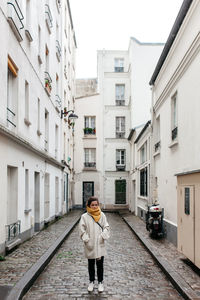 Full length of woman standing amidst buildings on street in city
