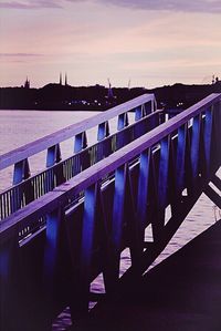 Pier over river against sky during sunset