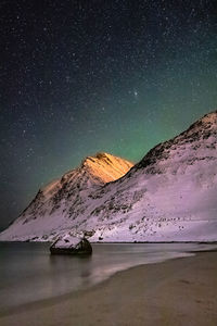 Scenic view of beach and mountains against sky at night